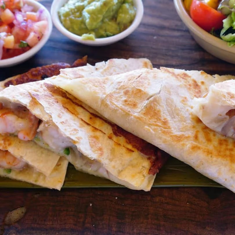 Shrimp quesadillas with pico de gallo and guacamole on a wooden table at Galindo's.